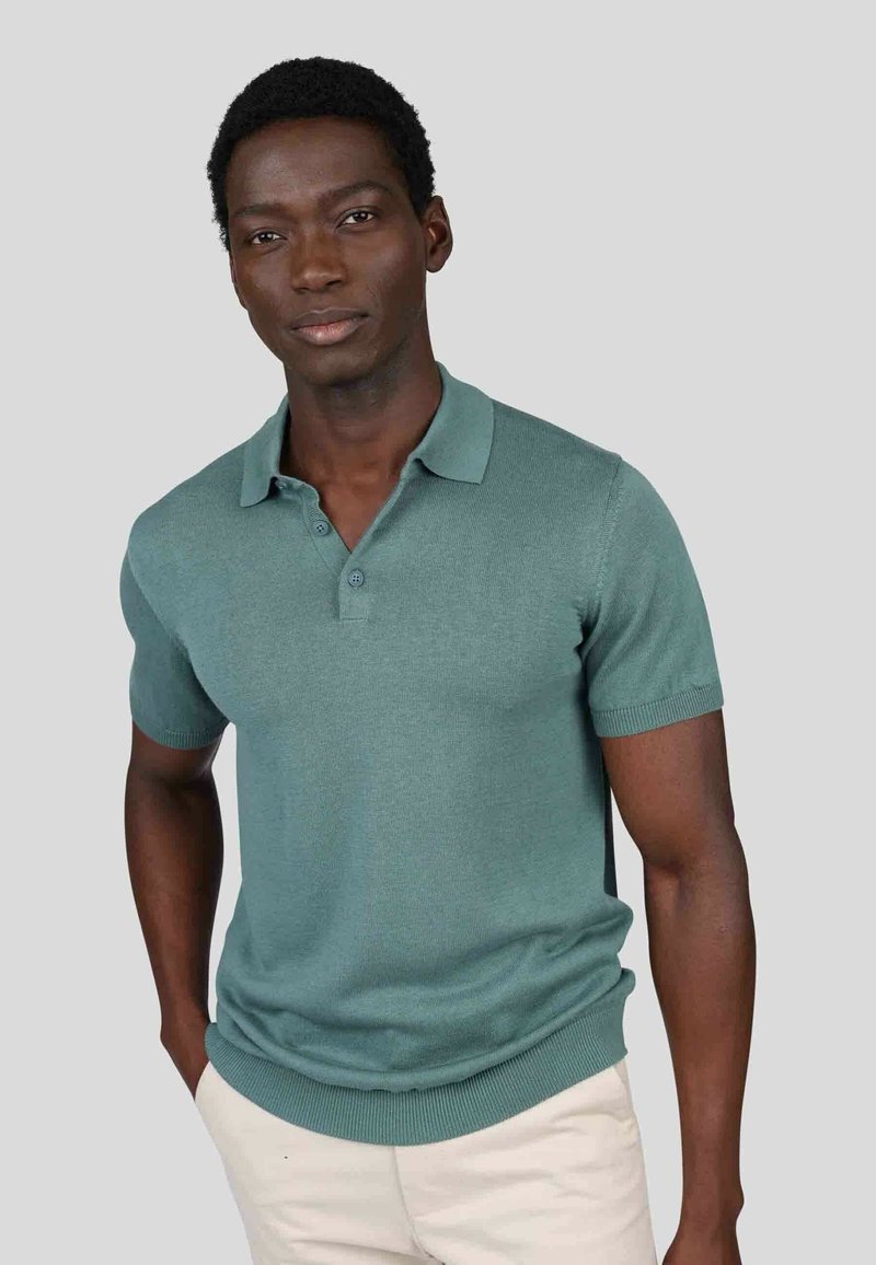 Polo à manches courtes en teal, en tissu tricoté avec un col et des poignets côtelés, doté d'une patte de boutonnage à deux boutons.