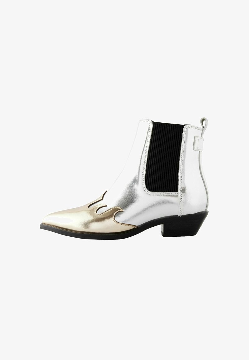 Botín metálico plateado y dorado con punta afilada, paneles laterales elásticos y un tacón pequeño. Presenta diseños recortados en la punta.