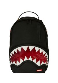 Mochila negra con diseño de boca de tiburón; presenta acentos rojos brillantes y dientes blancos. Material suave con un asa en la parte superior y cierre de cremallera.