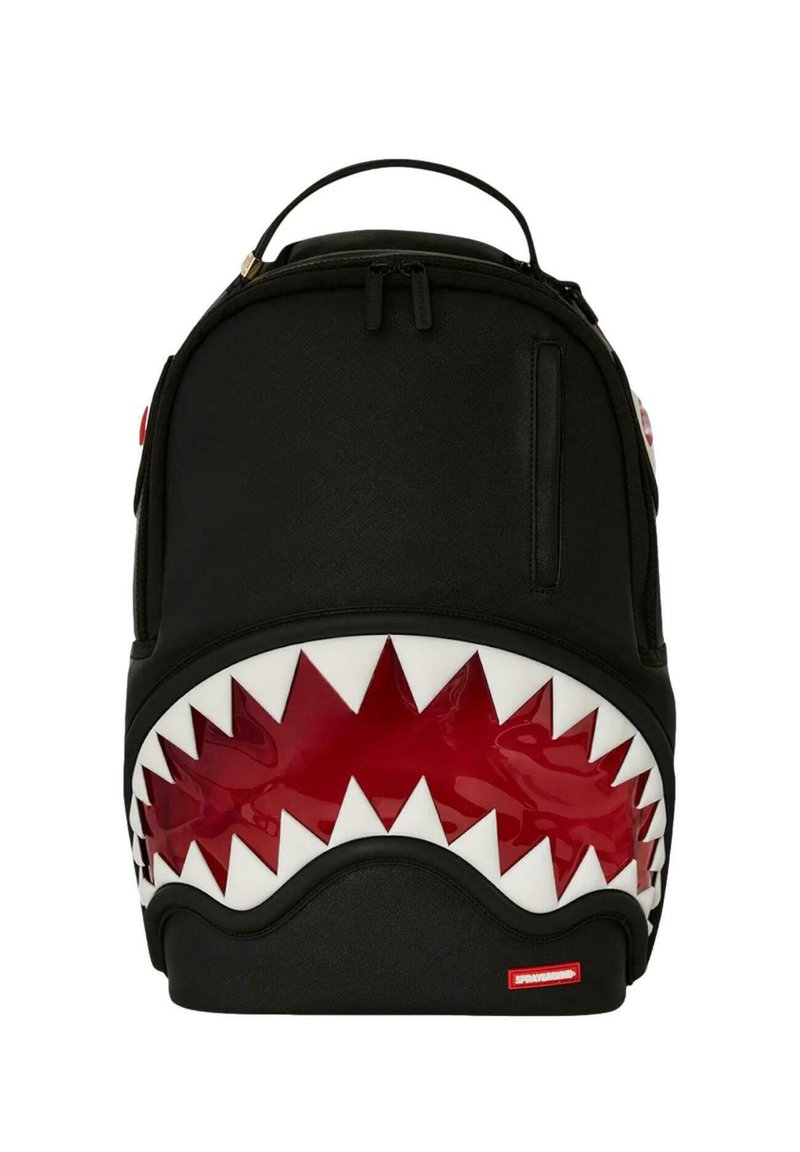 Mochila negra con diseño de boca de tiburón; presenta acentos rojos brillantes y dientes blancos. Material suave con un asa en la parte superior y cierre de cremallera.