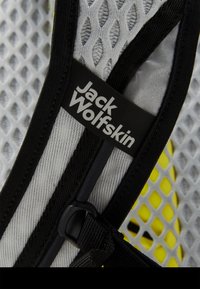 Tissu en maille gris avec un motif en nid d'abeille, bord noir et intérieur jaune. Présente une boucle en plastique noir et une étiquette "Jack Wolfskin".