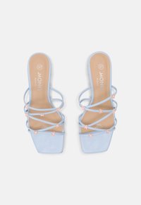 Světlé modré veganské kožené sandály se čtveratou špičkou, s několika překříženými popruhy a malými růžovými květinovými akcenty na popruzích. Velikost 37.