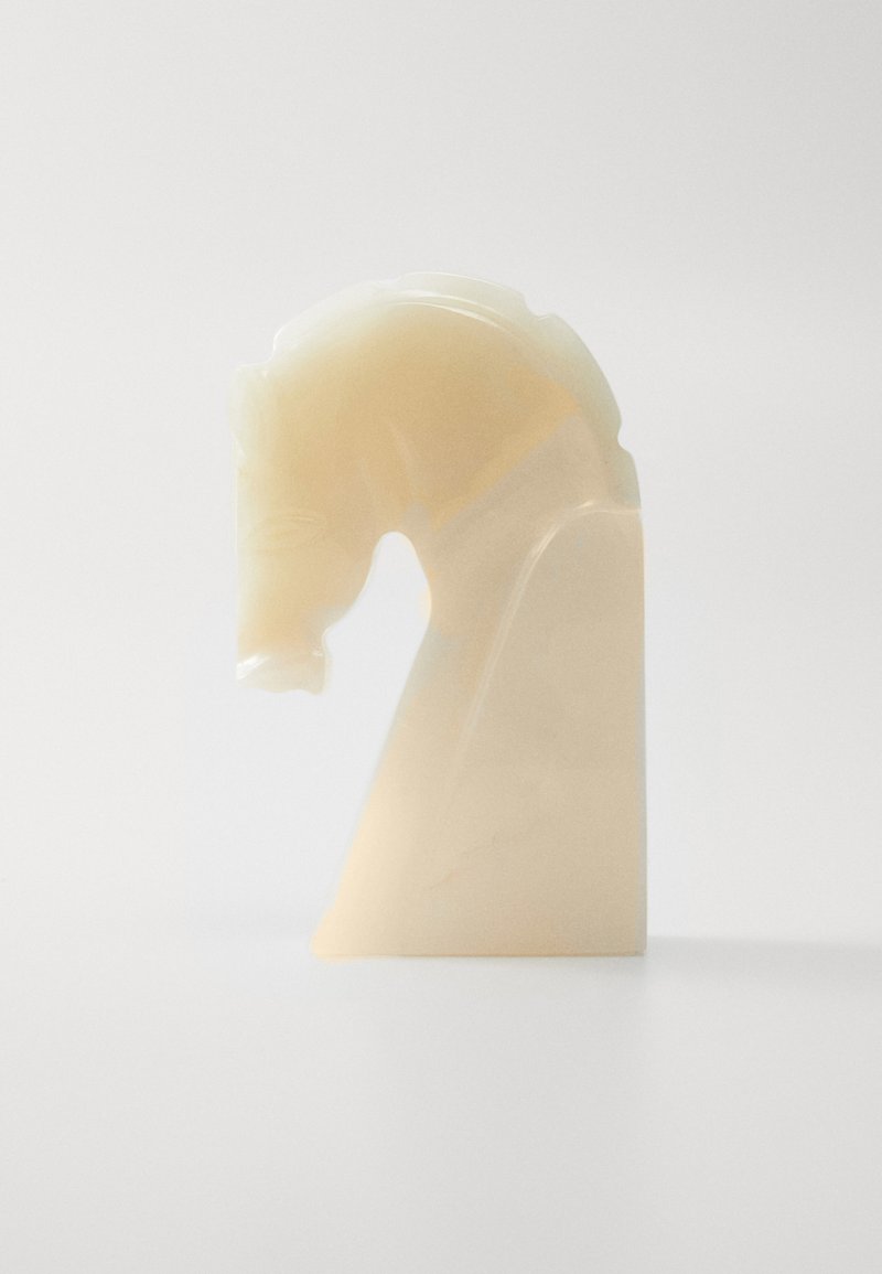 Puscaudīgs, gaišas krāsas sveķu šaha figūra, kas attēlo bruņinieku ar izsmalcinātu detaļu izstrādi un slīpu pamatni, demonstrējot gludu, spīdīgu tekstūru.