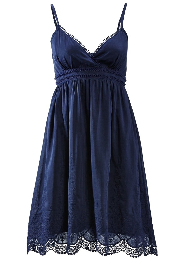 Námořnická modrá bezramenná šaty s výstřihem do V, krajkovým lemem, výšivkou a splývavou sukní. Disponuje krajkovým lemem ve tvaru vlny.