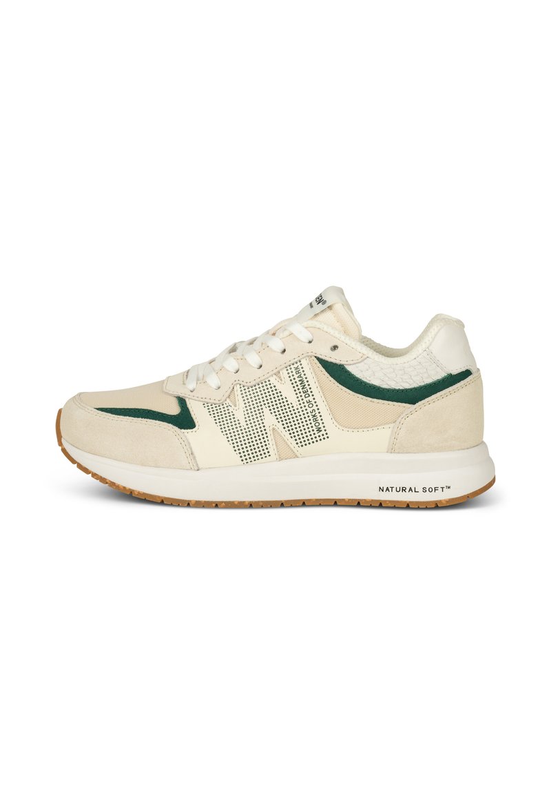 Baskets de sport beiges avec des accents verts, des panneaux en maille et un talon texturé. Présentent des lacets blancs et une semelle en caoutchouc, étiquetées "NATURAL SOFT™."