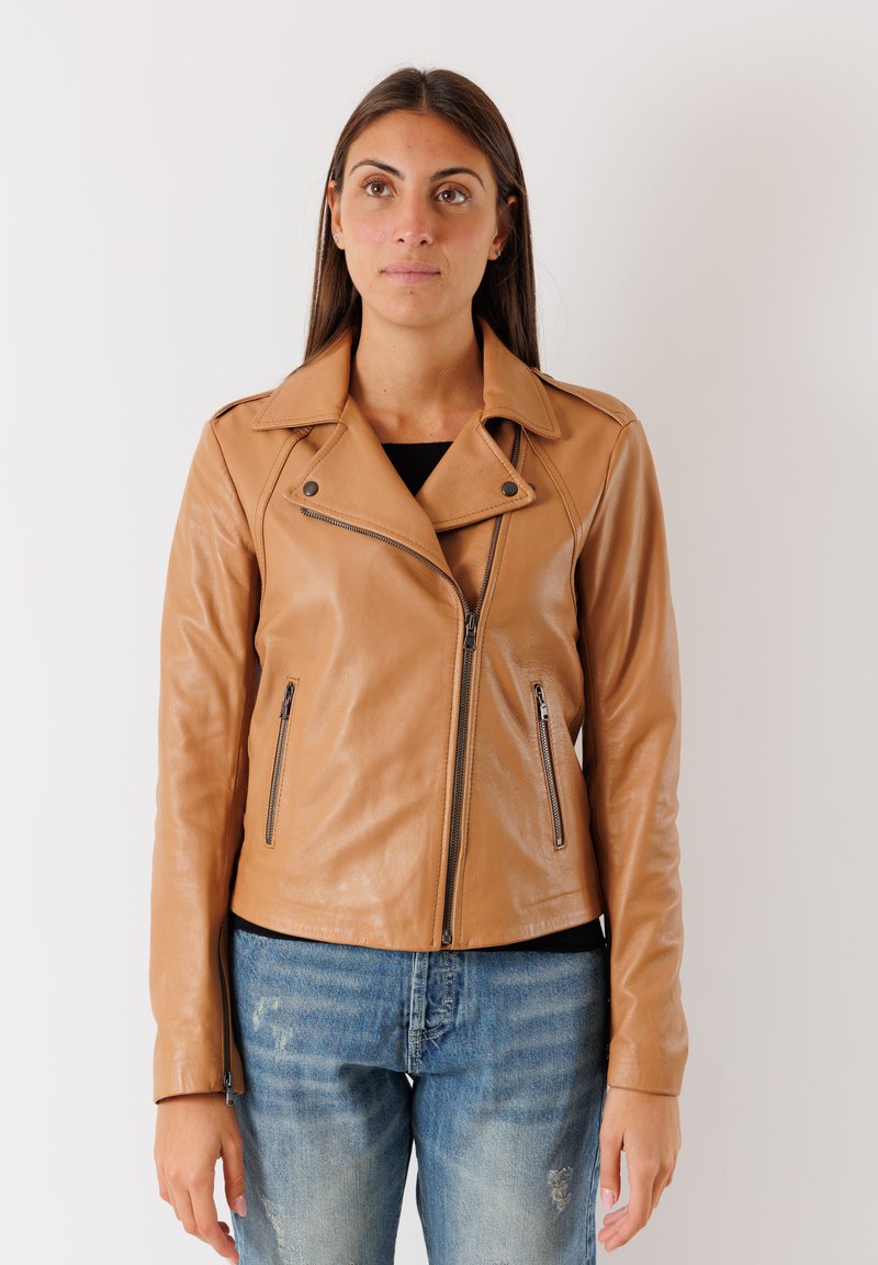 Giubotto da moto in pelle color cuoio con colletto a rever, chiusura con zip asimmetrica e due tasche anteriori con zip. Texture liscia con hardware minimale.