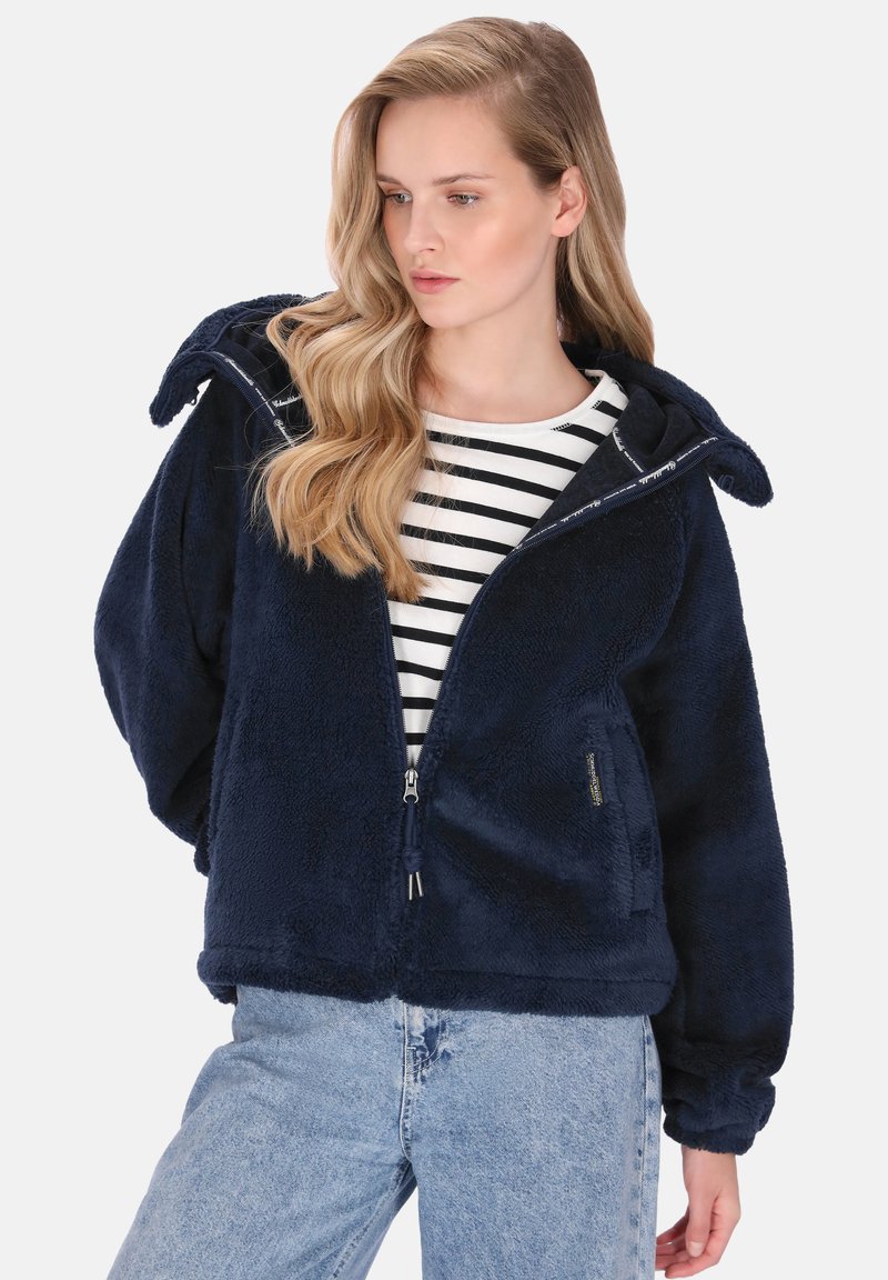 Granatowa polarowa kurtka z kapturem, zapinana na zamek, wykonana z teksturowanego materiału, z elastycznymi mankietami. W zestawie z czarno-białą koszulką w paski pod spodem.