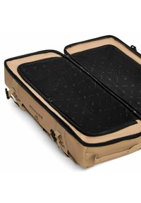 Sac de voyage beige avec un compartiment en maille zippé. Comprend deux compartiments avec des intérieurs en maille noire et des zippers robustes.