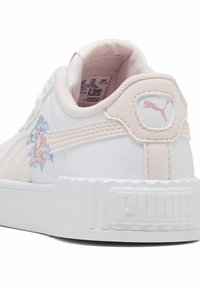 Biała skórzana tenisówka z różowymi akcentami, kwiatowym haftem, teksturowaną gumową podeszwą i wyraźnym logo PUMA na pięcie.