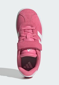 Zapatilla de ante rosa con acentos blancos, lengüeta acolchada y correa de velcro. Punta redondeada y forro interior texturizado. Suela de goma ligera.