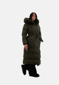 Giacca piumino verde oliva con cappuccio foderato in pelliccia removibile, cintura, maniche lunghe, silhouette over size e due tasche anteriori.