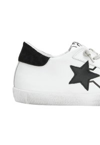 Sneaker bianco in pelle con design a stella nera, lacci grigi e linguetta sul tallone in suede nera. Suola in gomma testurizzata con leggero usura.