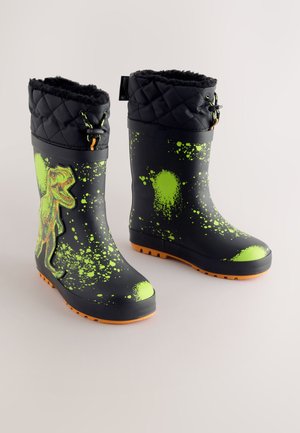 Juodi lietaus batai su žaliu dėmelių raštu, šone dizainas su dinozauru. Dirbtinio kailio pamušalas ir gumine oranžinės spalvos padu su protektoriumi.