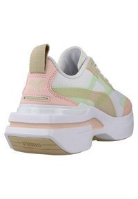 Baskets blanches avec des accents roses et verts, tige en maille texturée, col rembourré et semelle blanche épaisse avec des détails rose clair et beige.