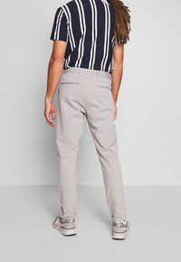 Grijze broeken met een ontspannen pasvorm, met een platte voorkant, twee achterzakken en een subtiele textuur, gecombineerd met een gestreept marineblauw shirt.