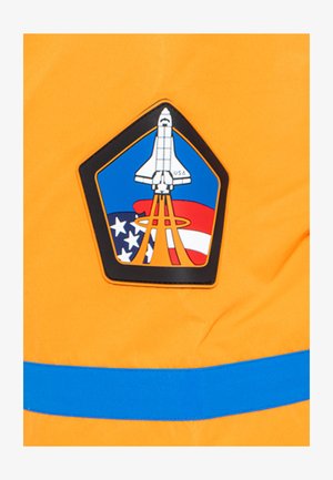 Un tessuto arancione brillante presenta una spilla esagonale nera con un disegno di uno space shuttle, accenti blu e uno sfondo con la bandiera americana.