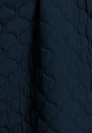 Marineblauwe gewatteerde stof met een golvend, reliëfpatroon, een gladde textuur en subtiele glans. Ideaal voor buitenshuis of bedtoepassingen.