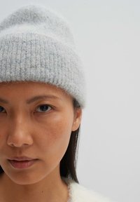 Berretto a maglia grigio chiaro con texture a coste e un aspetto morbido e soffice. Il cappello è a doppio strato per garantire calore.