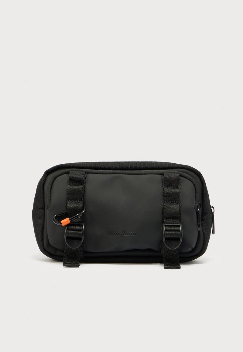 Μαύρο θήκη από νάιλον με δύο φερμουάρ, κάθετες ιμάντες, κλιπ καραμπίνερ και ανάγλυφο λογότυπο. Λείο υφή και συμπαγής ορθογώνιος σχήμα.