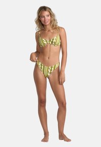 Green patterned bikini set featuring a distinctive wavy design, supportive bra with adjustable straps, and low-rise bottoms.