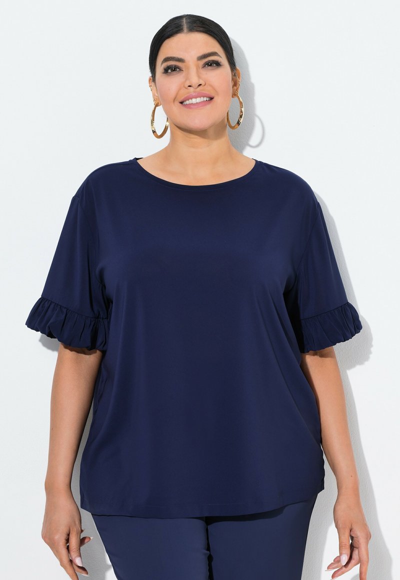 Top blu navy realizzato in tessuto morbido, con maniche corte arricciate e scollatura rotonda. Silhouette semplice e rilassata con una texture morbida.