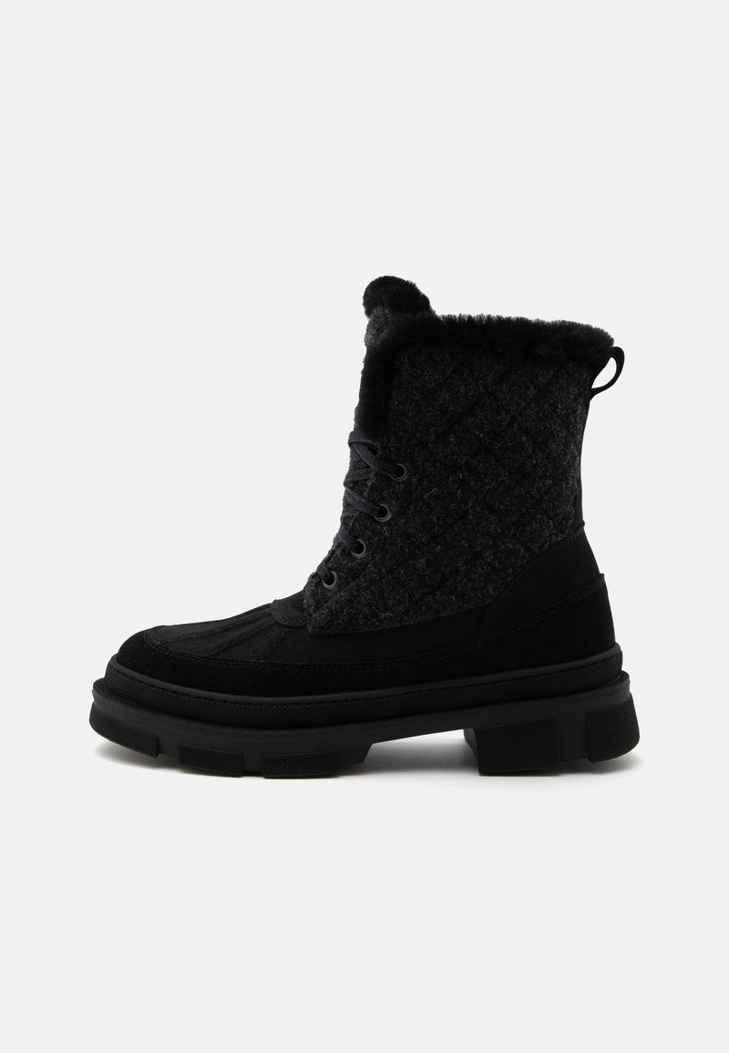 Botte d'hiver noire avec dessus matelassé, doublure en fourrure, lacets à l'avant et semelle épaisse à crampons, conçue pour temps froid.