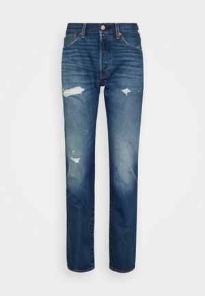 Jean en denim bleu coupe droite, présentant des zones délavées et des déchirures usées sur l'avant des cuisses et aux genoux.