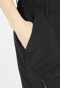 Svarta joggingbyxor med elastisk midja, sidofickor och ficka med dragkedja. Slät tygkvalitet.