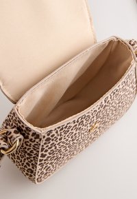 Handtas met luipaardprint en gouden details, zachte beige binnenvoering en een gestructureerde vorm. Open bovenzijde die de binnenruimte toont.