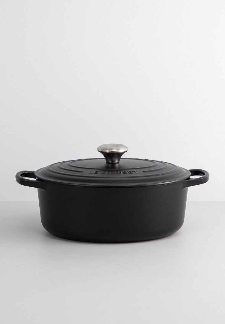 Schwarzer gusseiserner Dutch Oven mit glänzender Oberfläche, runder Form und metallischem Knopf auf dem Deckel. Verfügt über zwei seitliche Griffe für einfaches Anheben.