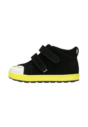 Zapato negro de niño con caña alta, dos tiras de velcro, puntera blanca reforzada y suela de color amarillo brillante.