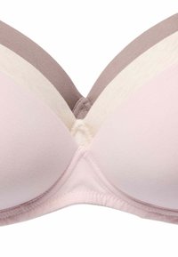 Drei nahtlose, gepolsterte BHs übereinandergestapelt, Farben von vorne nach hinten: Hellrosa, Beige und Mauve, mit sichtbaren Körbchen und Mittelnaht.