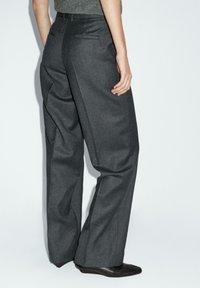 Graue maßgeschneiderte Hosenträger mit hoher Taille und weitem Bein, aus glattem Stoff gefertigt, mit Gesäßtaschen und einer schlanken Silhouette.