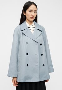 Φωτεινό γαλάζιο διπλόπετο παλτό με φαρδύ πέτο, μαύρα κουμπιά και δύο πλαϊνές τσέπες. Κατασκευασμένο από απαλό ύφασμα με άνετη εφαρμογή.