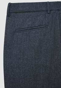 Pantaloni in tessuto blu scuro con una texture liscia, silhouette frontale piatta con una tasca posteriore singola e un design classico della vita.