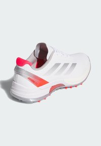 Witte sportschoen met zilveren en rode accenten, met een gestructureerde bovenkant, gewatteerde kraag en een profielzool voor grip.
