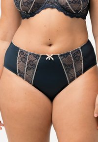 Marineblaue hochgeschnittene Unterhosen mit hautfarbenen Spitzenpaneelen, gewellten Kanten und einer kleinen Schleife in der Mitte, verziert mit dekorativen Nähten.