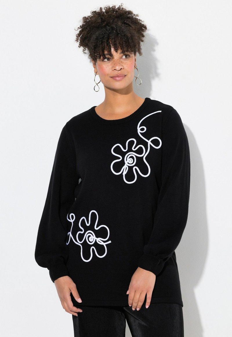 Schwarzer Pullover aus weichem Strickmaterial mit weißen floralen Mustern auf der Vorderseite und langen Ärmeln mit gerippten Bündchen.