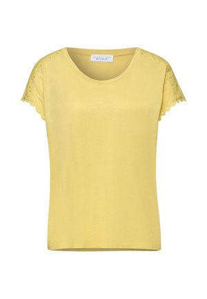 Top jaune femme à manches courtes avec col rond et détails décoratifs découpés le long des manches et bords festonnés.