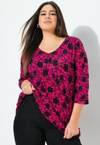 V-Ausschnitt-Tunika im schwarzen und fuchsiafarbenen Blumenmuster, mit drei Viertelärmeln und lockerer Passform, aus leichtem Stoff.