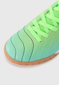 Groene gradient sportschoen met een gestructureerde bovenkant, dikke veters en een rubberen zool. Heeft gebogen stiksels en een afgeronde tekening.