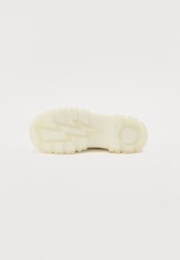 Translucent rubber shoe sole featuring a zigzag pattern, rounded edges, and a circular accent near the heel area. Soft, matte finish.