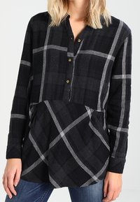Camicia a maniche lunghe a quadri nera e grigia, con colletto a bottoni, motivi contrastanti e vestibilità comoda. Tessuto morbido con finitura testurizzata.