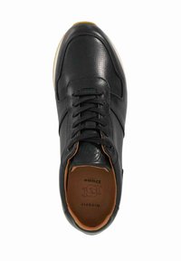 Black leather sneaker with a smooth texture, round toe design, perforated sections, and contrasting brown interior. Laced up with a logo emblem.