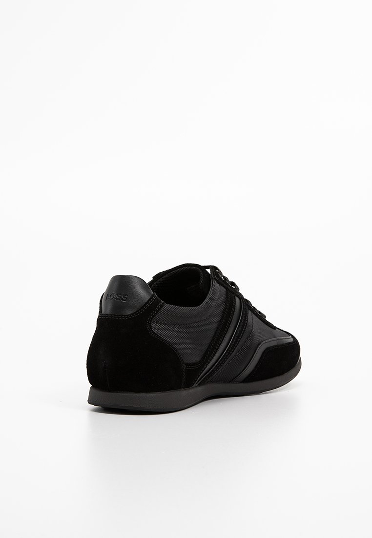 Basket noire avec une combinaison de cuir lisse et de maille texturée. Design profil bas et col rembourré avec un branding discret au niveau du talon.