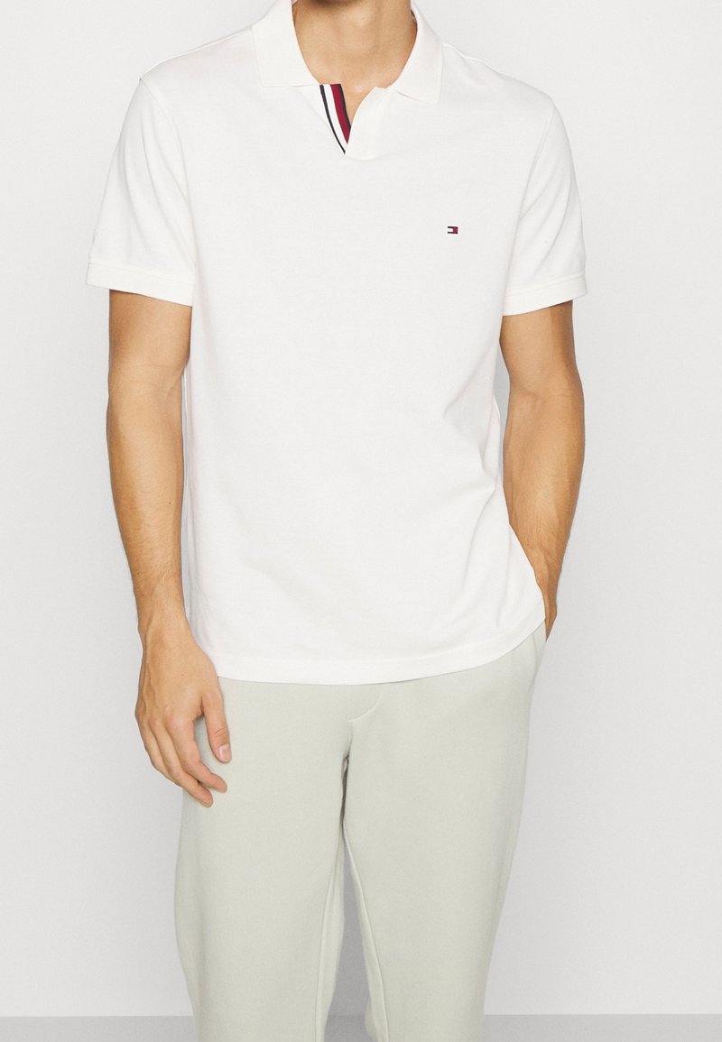 Polo shirt bianco in cotone, con colletto e dettaglio a righe sul colletto. Logo piccolo sul petto.
