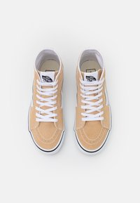 Tan suede high-top sneakers with white laces, round toe, contrasting black and white rubber sole, and Vans logo on the tongue.
