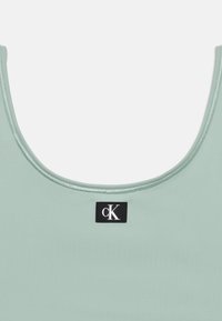 Φωτεινό πράσινο αμάνικο τοπ με στρογγυλή λαιμόκοψη και μικρή μαύρη ετικέτα με λευκό λογότυπο «cK» στο κέντρο μπροστά.