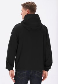 Chaqueta negra con capucha, puños y cinturilla elásticos, con una textura suave y un diseño minimalista. Sin logotipos ni patrones visibles.