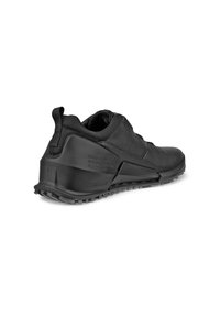 Scarpa sportiva nera con tomaia in pelle texture, suola in gomma e linguetta posteriore. Presenta un design elegante e un tacco rialzato per supporto.